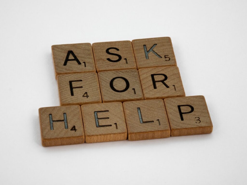 Wooden letter tiles spelling ASK FOR HELP representing business questions and customer support