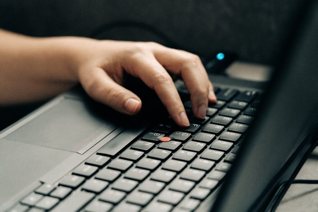 Hands typing on laptop keyboard for content creation and writing with AI assistance