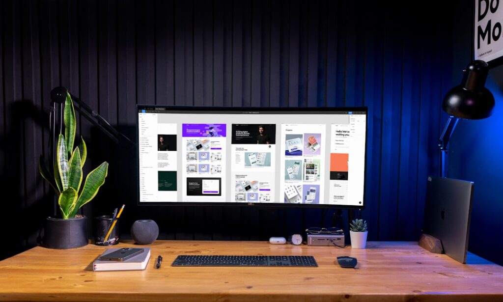 Creative digital design workspace with computer monitor displaying various design projects and mood boards