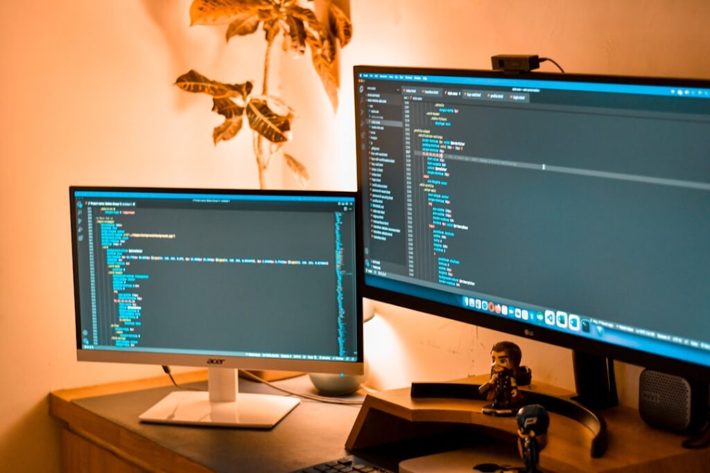 Dual monitor setup showing code development with AI programming tools
