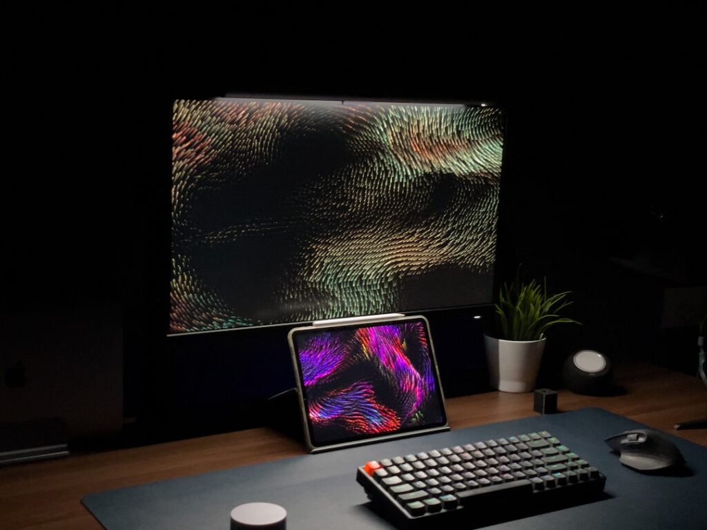 Minimalist desk setup displaying colorful digital artwork on computer monitors, representing AI image and video generation tools