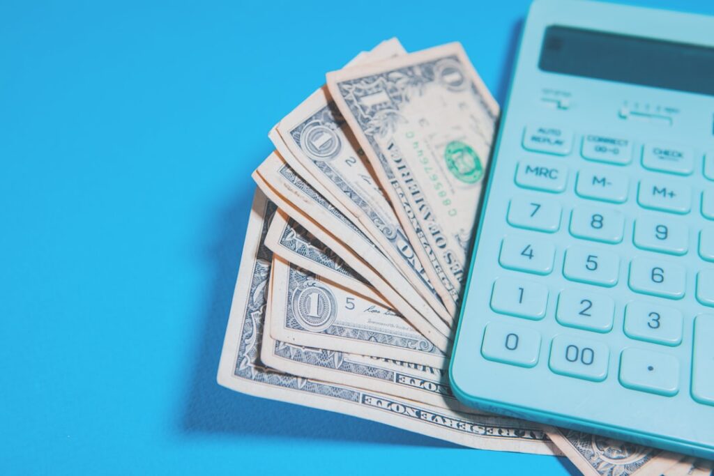 Calculator and dollar bills representing web hosting pricing analysis and budget planning