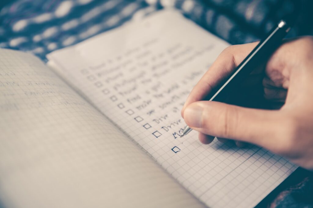 Person working through a checklist with pen and paper, representing a systematic decision-making framework for choosing hosting