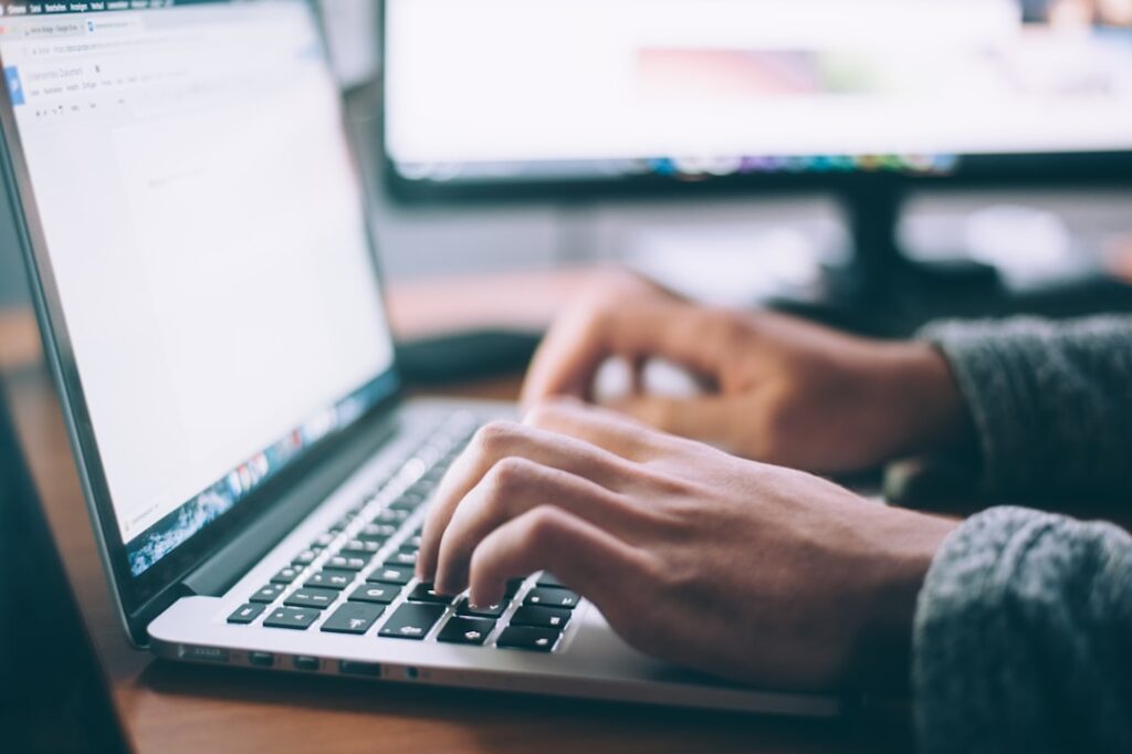 Person typing on laptop computer for AI-assisted writing and content creation