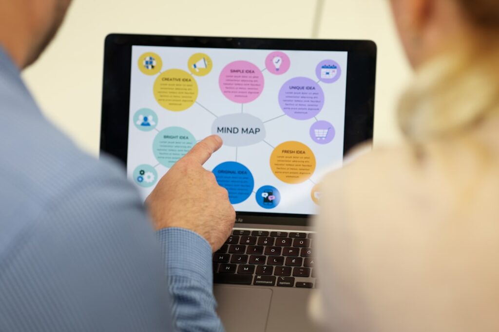 Two people viewing a decision-making mind map on laptop for choosing software tools