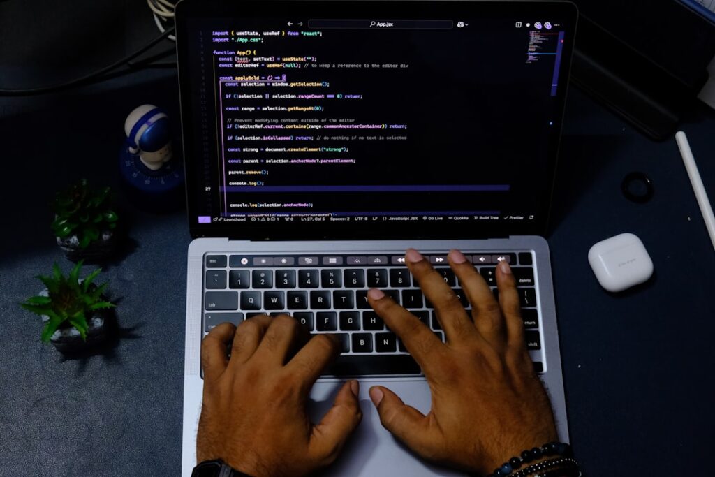 Developer hands typing code on laptop computer with AI coding assistance