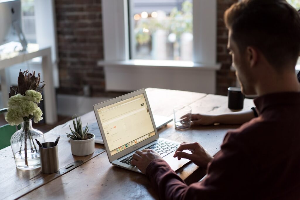 Small business owner working on a laptop at a desk, evaluating website hosting options for their business.