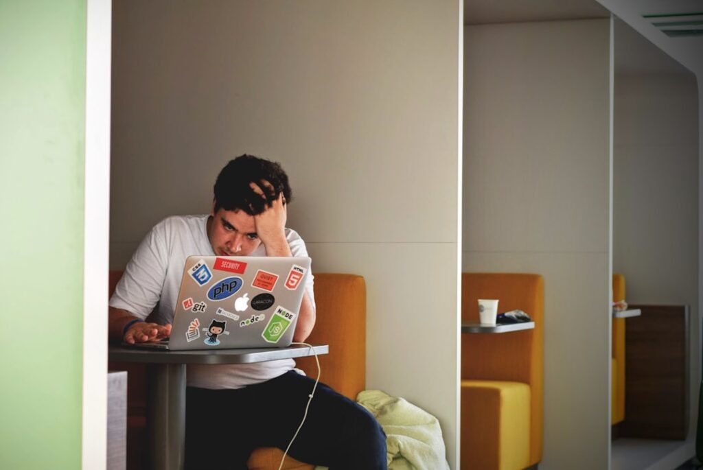 Person looking stressed and overwhelmed at a laptop, representing the confusion of comparing domain hosting providers