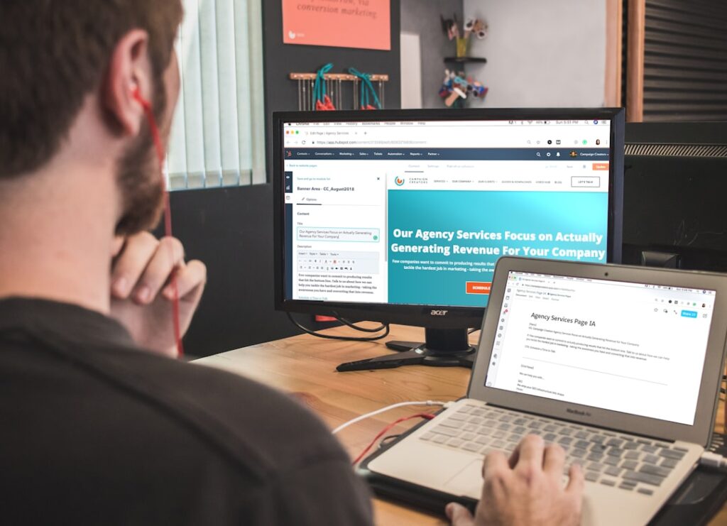 Person reviewing a website design on dual monitors, representing comparing Elementor Free vs Pro plans
