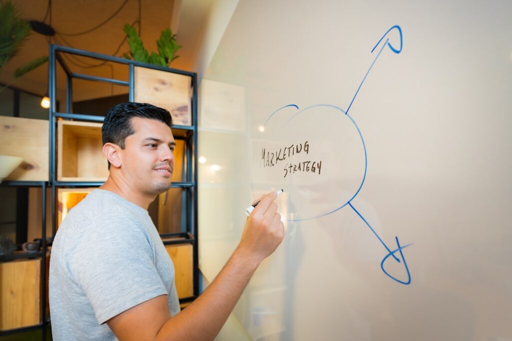 Small business owner planning hosting strategy on whiteboard, representing the decision-making framework for choosing website hosting