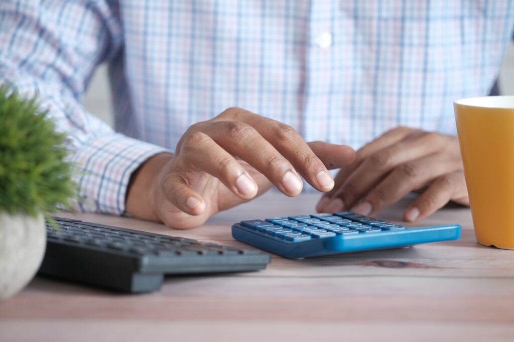 Person calculating hosting costs and pricing with calculator