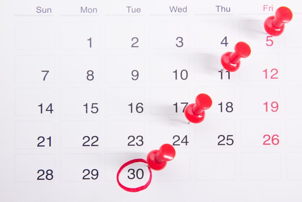 Calendar with red push pins marking renewal dates, representing annual software subscription billing cycles