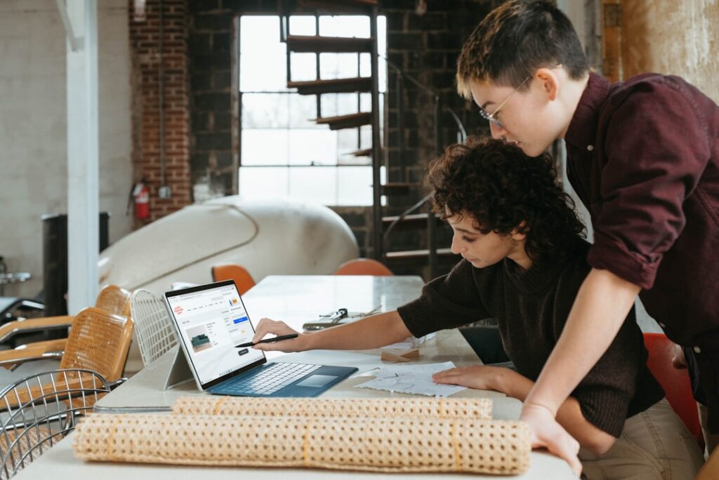 Two people collaborating over a laptop screen, representing the process of learning WordPress as a beginner or small business owner