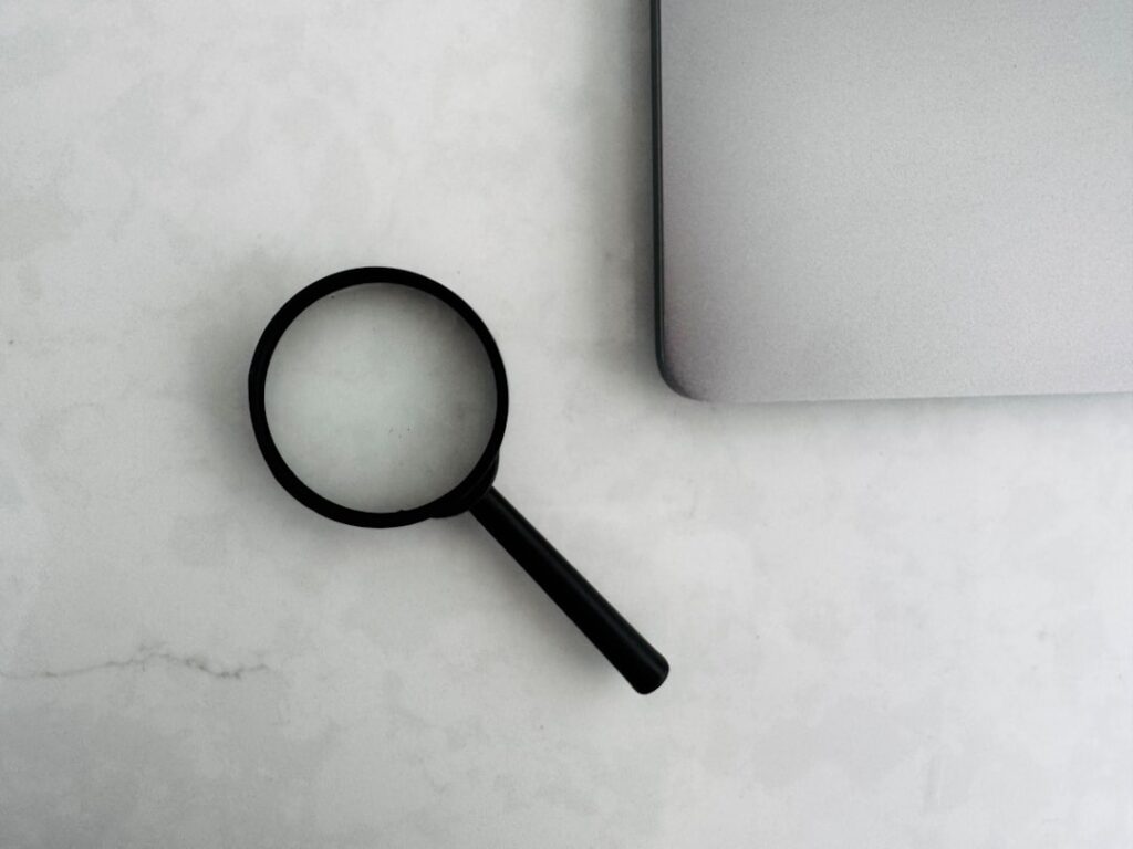 Magnifying glass next to laptop representing research and fact-checking capabilities of AI search tools