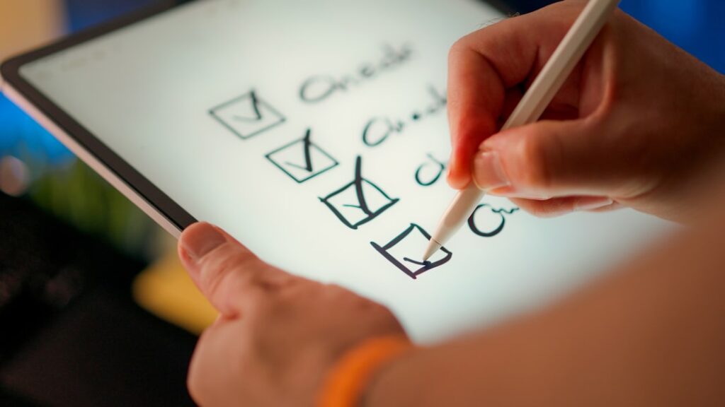 Hand checking off items on a digital checklist tablet, representing a structured decision framework for choosing domain hosting
