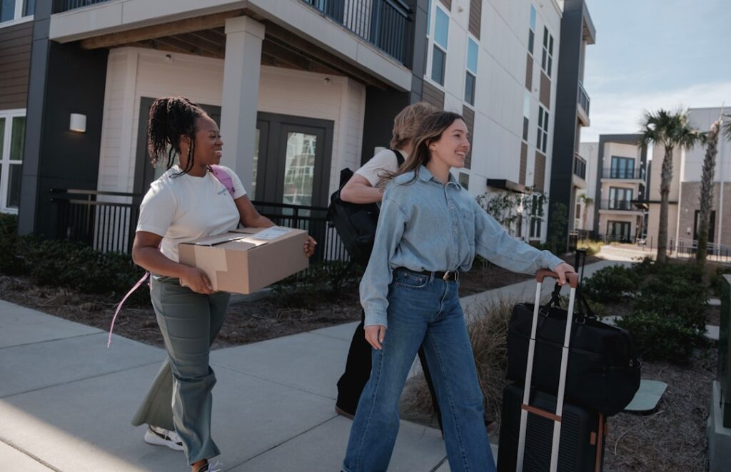 Young people moving into a shared apartment building with boxes and luggage, illustrating the shared hosting analogy