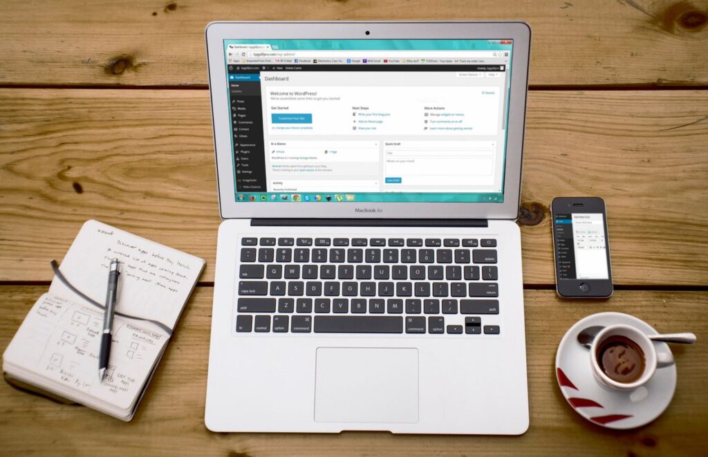 WordPress dashboard open on a laptop with a notebook and coffee on a wooden desk