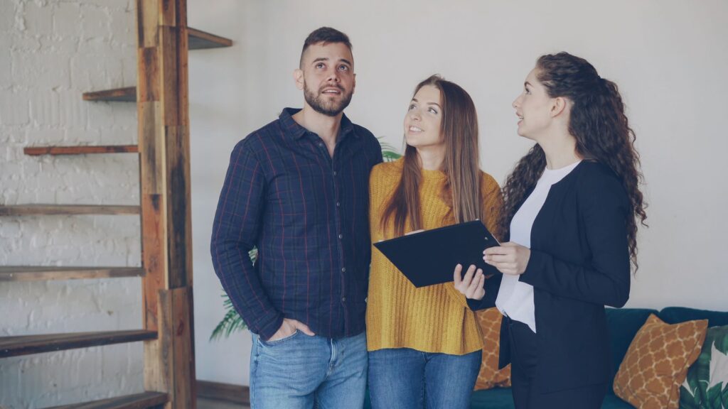 Real estate agent showing a property to a young couple buyers inside a modern home