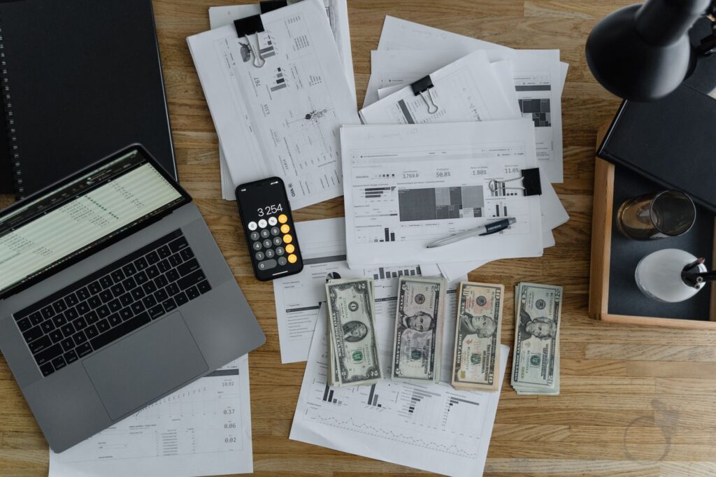 Financial documents, cash, and a laptop on a desk representing website cost planning and budget breakdown