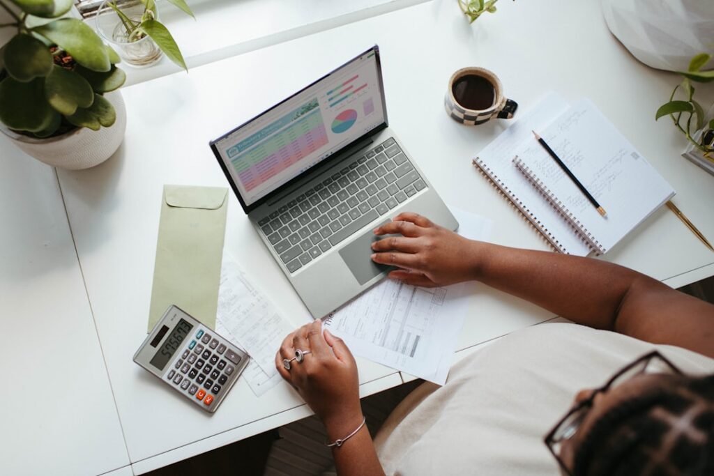 Person reviewing financial charts and data on a laptop with a calculator and notebook on a clean desk, representing ROI analysis and cost-benefit decision making