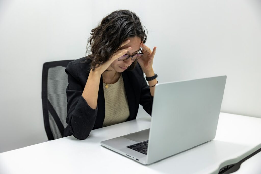 Stressed woman with hands on temples looking at laptop screen, representing the frustration of WordPress problems. Photo by Yan Krukau.