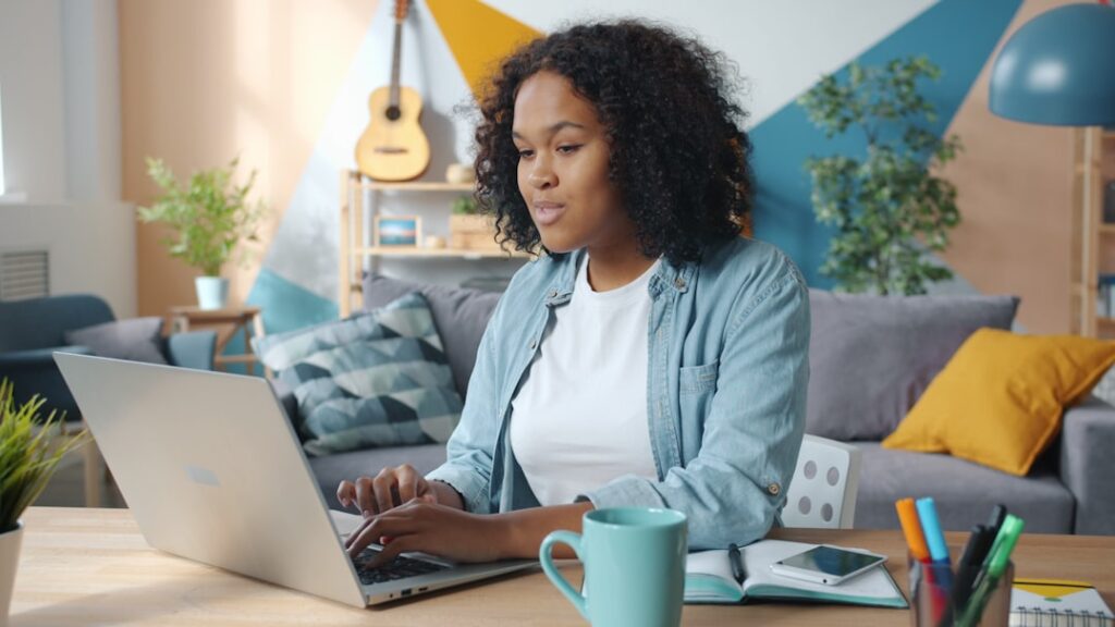 Woman working from home on a laptop with a mug and notebook nearby — a solopreneur or small business owner choosing the right free AI tools for their workflow